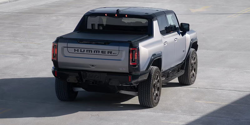 Rear view of silver and black GMC Hummer EV pickup parked on a concrete surface.